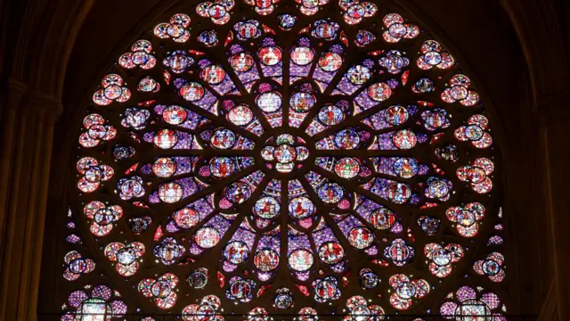 Circular window of the cathedral that has stained glass in several shades of pink, purple and blue