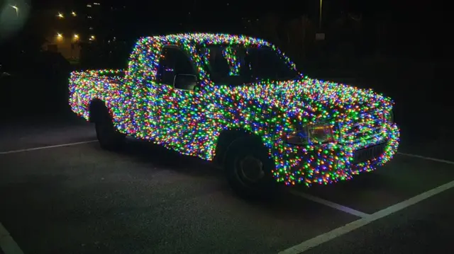 A Ford fiesta covered in multi-coloured lights in a car park