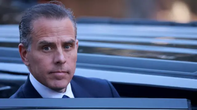 Hunter Biden in suit, exiting car with his head above the open door