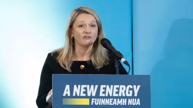 Emer Currie stands in front of a blue podium