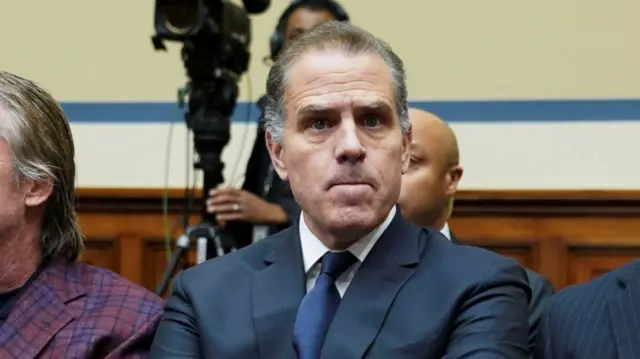 Hunter Biden during surprise appearance at a House Oversight Committee. He's sitting down on chair wearing a dark-grey suit, blue tie and white shirt looking slightly to his left