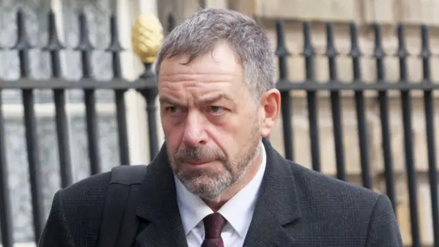 Tony Chambers, wearing a suit and tie, near some metal railings