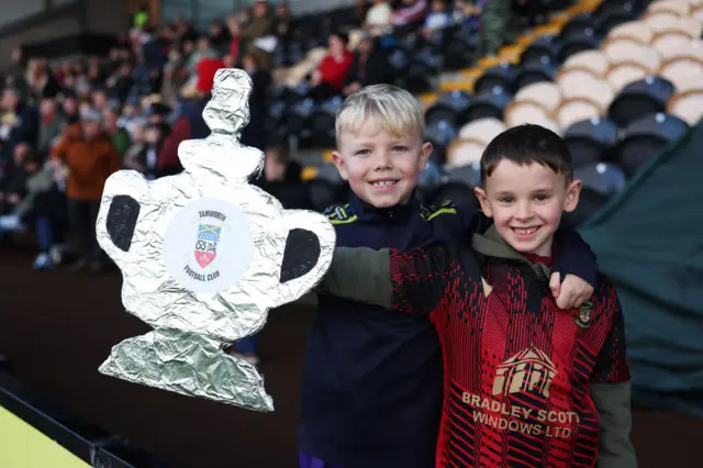 Fans of Tamworth pose for a photo with a tin foil FA Cup Trophy