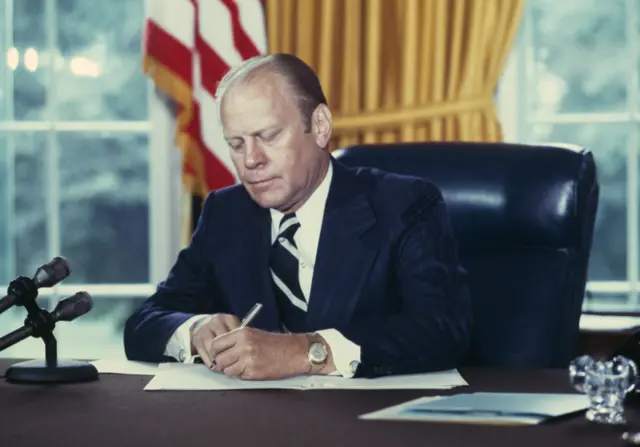 US President Gerald Ford signing a document granting former President Richard Nixon a full pardon in 1974