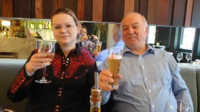 Sergei and Yulia Skripal posing for a photo in a restaurant, holding up their glasses