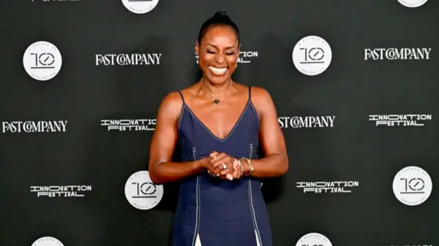 Issa Rae wearing a v-neck navy dress stood at a red carpet event