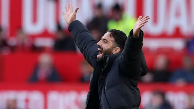 Ruben Amorim with both hands in the air celebrating.