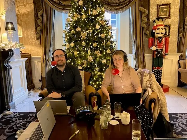 Dr Caoilfhionn D'Arcy from Maynooth University and Richard Morgan of Radio Ulster. Richard is wearing a black shirt and a headset with a red microphone. Dr D'Arcy has blone hair and is wearing a similar headset and a tan-coloured cardigan