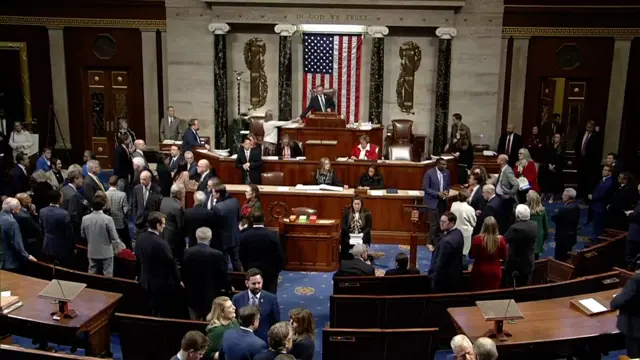 Lawmakers stand around in the House of Representatives while voting happens