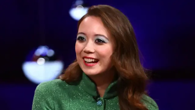 A woman with shoulder length brown hair in a green top