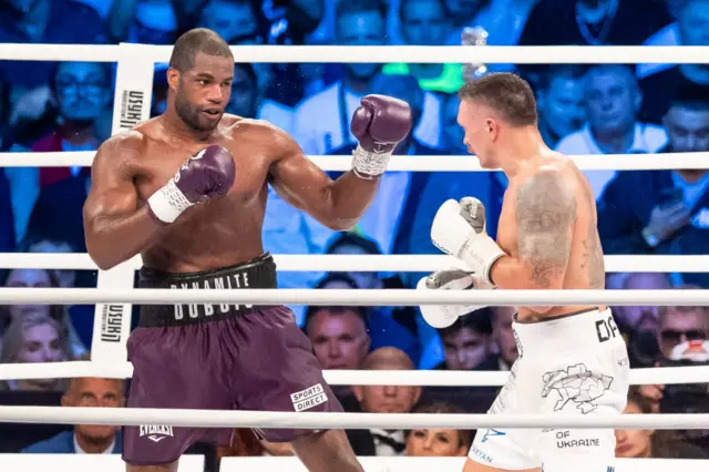 Daniel Dubois holds up his gloves in front of Oleksandr Usyk