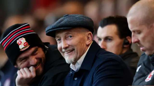 Swindon Town boss Ian Holloway smiling as he watches his side play Accrington Stanley