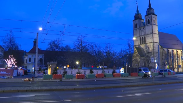 A picture of the Christmas markets with police tape across an entrance and two police vehicles parked up. There's a church in the background, and a road in the foreground. It's just starting to get light outside.