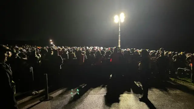 A blurry dark picture of a large crowd in front of a spotlight