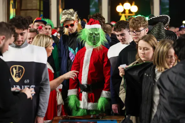 A sepctator in green facepaint and Father Christmas outfit at Alexandra Palace