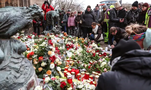 Dozens of people gather around flowers and candles which have been laid in Magdeburg