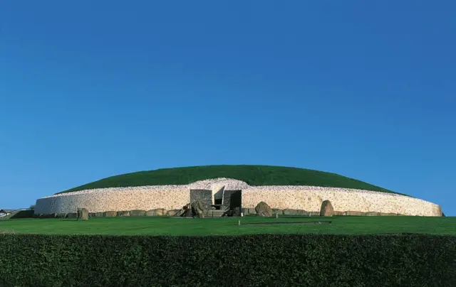 A large mound with white walls, a grassy top and a doorway