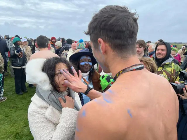 A man putting blue paint on a woman's head with his hand