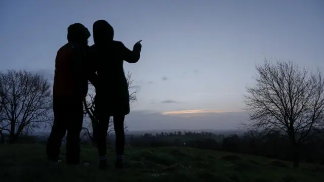 People stand on a hill at Navan Fort, also known as Emain Macha, in Armagh, which has been a significant site since 4,000BC - a large circular hilltop enclosure hosting gatherings of many of the great chieftains of old.