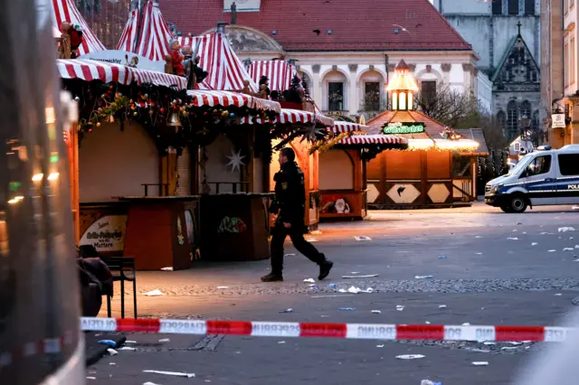 A police officer patrols a cordoned off area at the scene of a vehicle-ramming attack on the Christmas market in Magdeburg, Germany