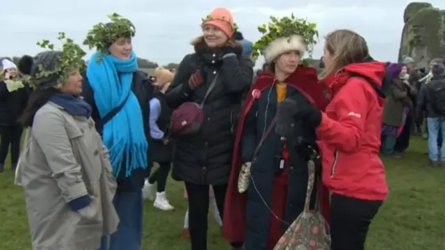 A group of four women wearing ivy crowns being interview by a reporter