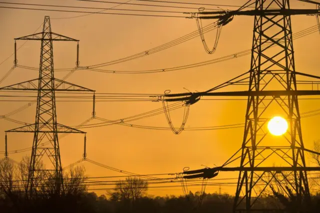 A winter sunrise, with the Sun visible through pylons.