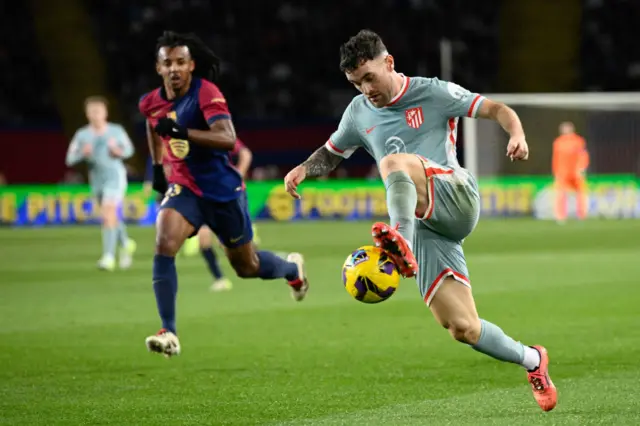 Atletico Madrid's Spanish defender #21 Javi Galan (R) controls the ball challenged by Barcelona's French defender #23 Jules Kounde