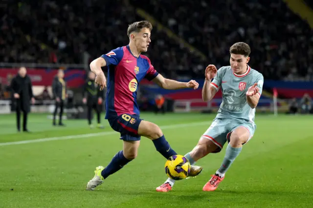 Gavi of FC Barcelona controls the ball whilst under pressure from Julian Alvarez of Atletico de Madrid