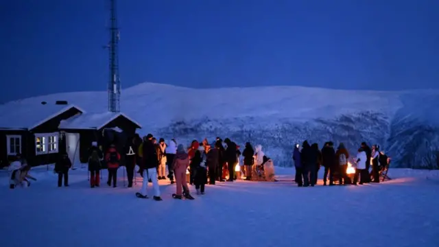 People gather around bonfires waiting for New Year’s Eve fireworks on Mount Floya in Norway last year