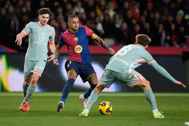 Barcelona's Brazilian forward #11 Raphinha (C) is challenged by Atletico Madrid's Spanish midfielder #08 Pablo Barrios (R) and Atletico Madrid's Argentine forward #19 Julian Alvarez