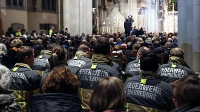 View of backs of emergency staff wearing high vis jackets at a memorial service at Magdeburg catherdral