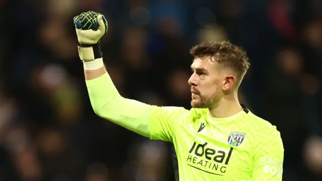 West Brom goalkeeper Alex Palmer holds his arm in the air in celebration