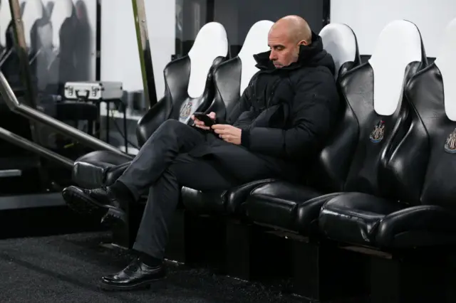 Pep Guardiola looking at his mobile phone before a game