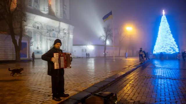 A man plays the accordion near Ukraine's main Christmas tree in Sophia Square on Christmas Eve, amid Russia's attack on Ukraine, in Kyiv, Ukraine, December 24, 2024.