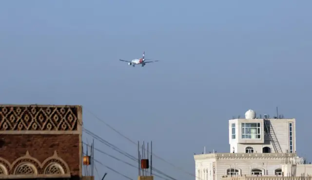 Wide show of tops of buildings in Sanaa, Yemen, with the back of a Yemenia Airways plane in the distance as it heads towards the international airport