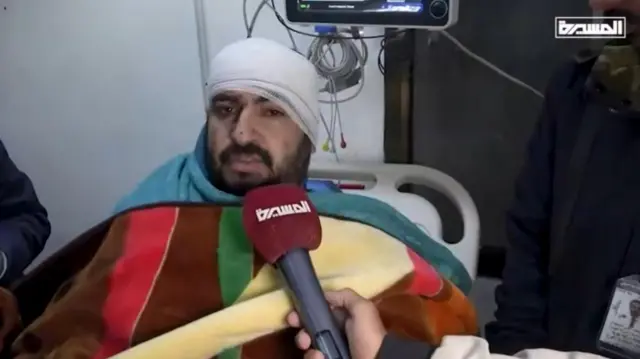 A man speaking to the camera with his head bandaged up