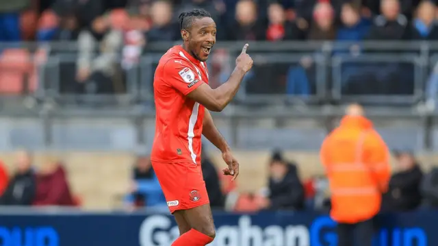 Omar Beckles smiles and points to the crowd after making it 3-0 to Orient against Crawley