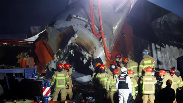 Rescuers work the wreckage of an aircraft that went off the runway and crashed