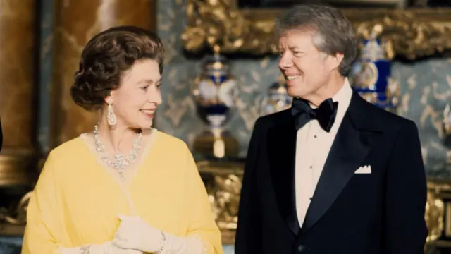 Queen Elizabeth II and Carter stand next to each other in formal attire