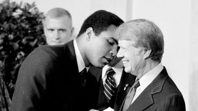 Muhammad Ali and Carter embrace as others look on