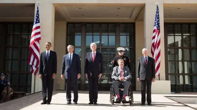 The presidents line up outside, flanked by US flags