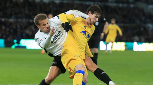 Derby's Kenzo Goudmijn grapples with Leeds' Brenden Aaronson