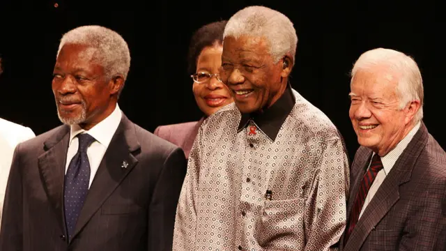 The three men stand in a line smiling