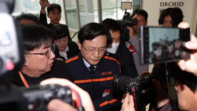 Jeju Air CEO Kim E-bae leaves the venue of a press conference held in Seoul, South Korea. He is surrounded by press and cameras