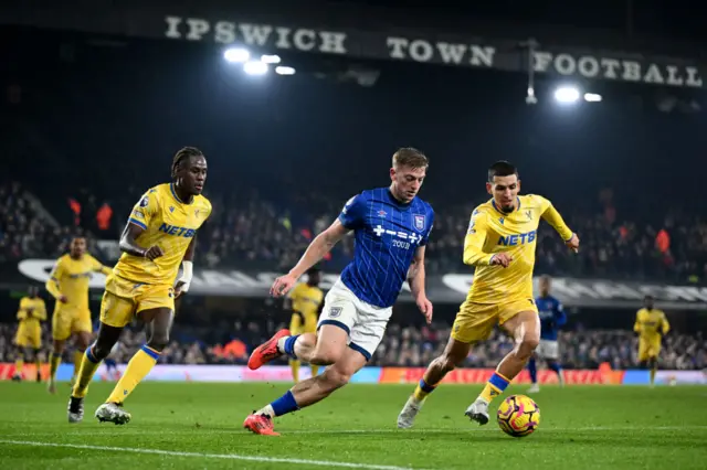 Liam Delap of Ipswich Town runs with the ball under pressure from Trevoh Chalobah and Daniel Munoz of Crystal Palace