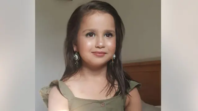 Sara Sharif with her hair loose, wearing make up, dangling earrings and a green dress