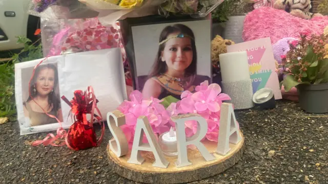 Tributes to Sara Sharif left outside her home, including a two photographs of Sara, cards, candles and flowers