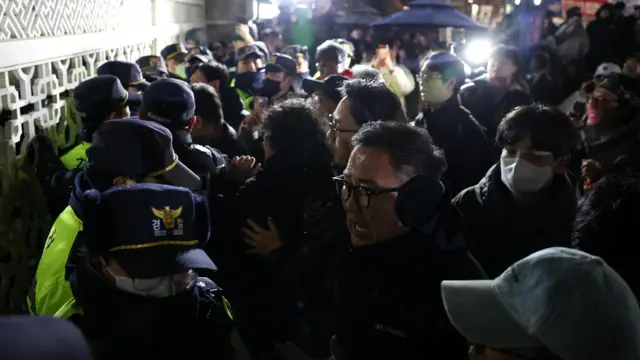 People react as police close the gate of the National Assembly