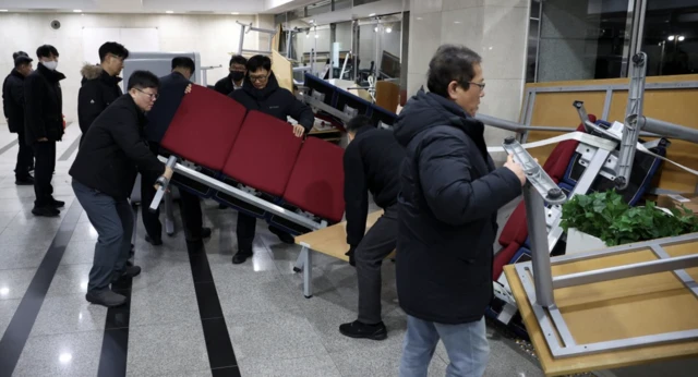 Officials remove the furniture barricades from the doors of the National Assembly building