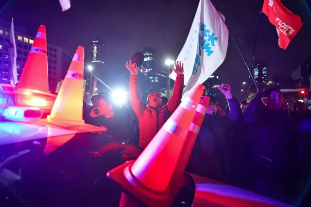 A protester throws his hands in the air near a police car